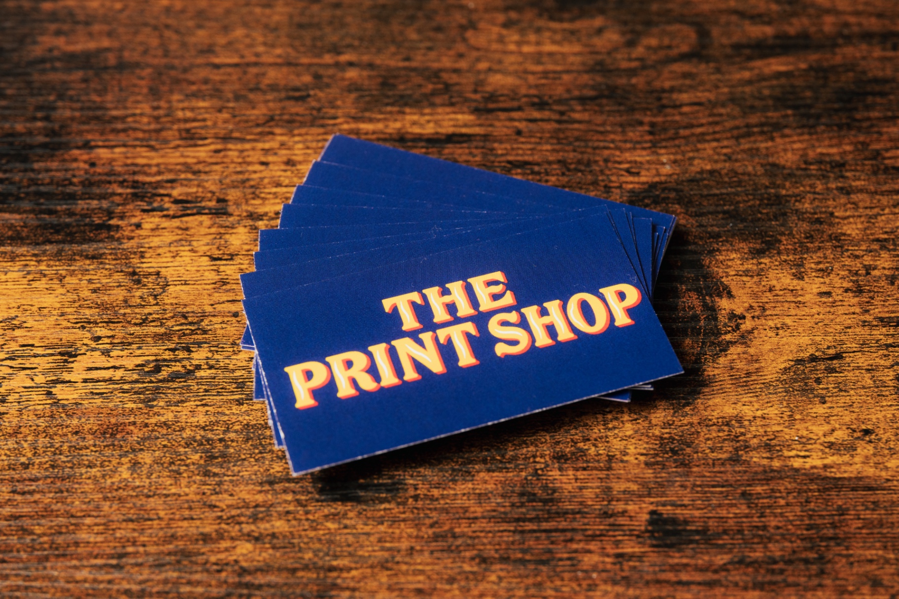 Stack of navy business cards with gold The Print Shop lettering