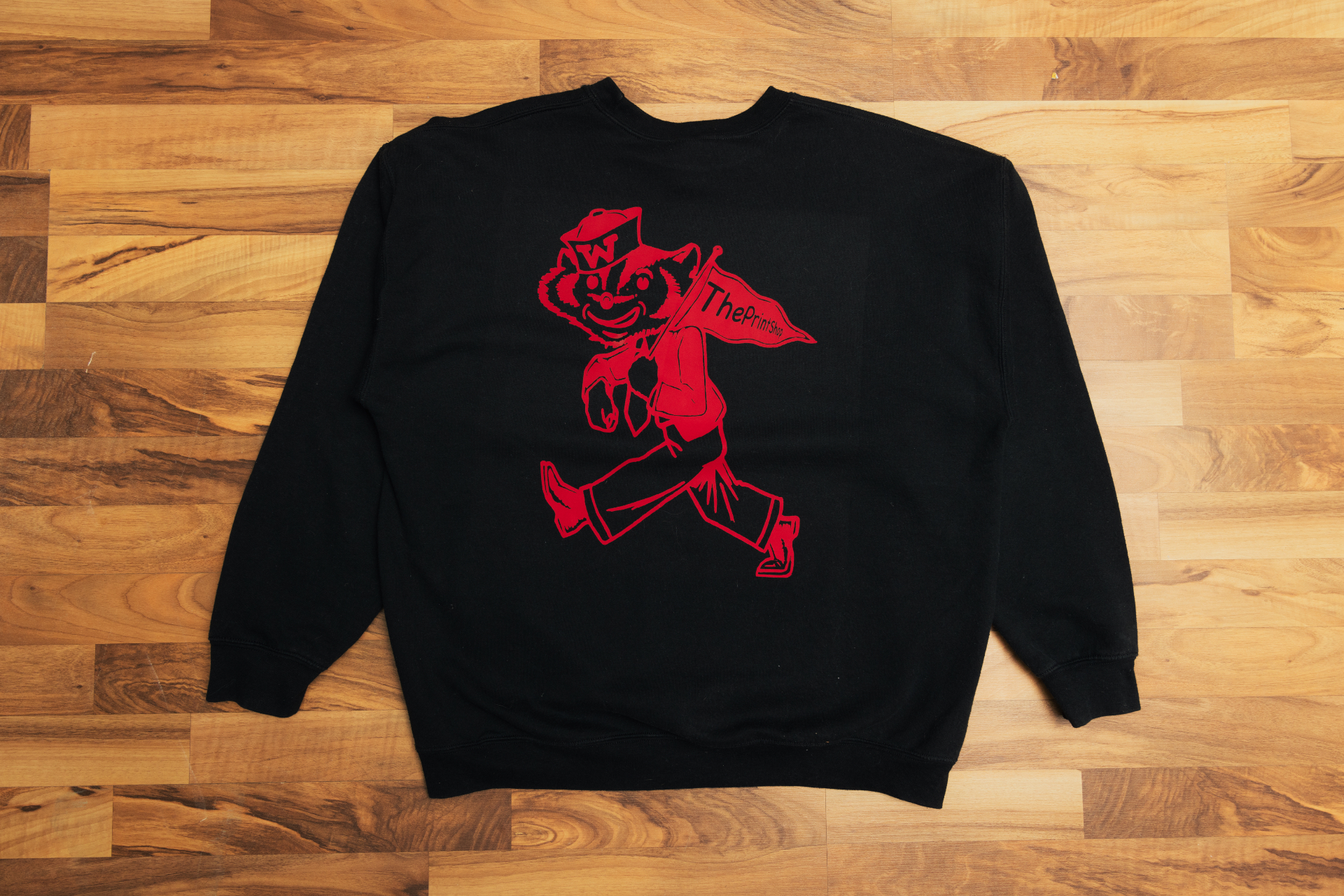Black crewneck with a red screen-printed mascot and The Print Shop pennant